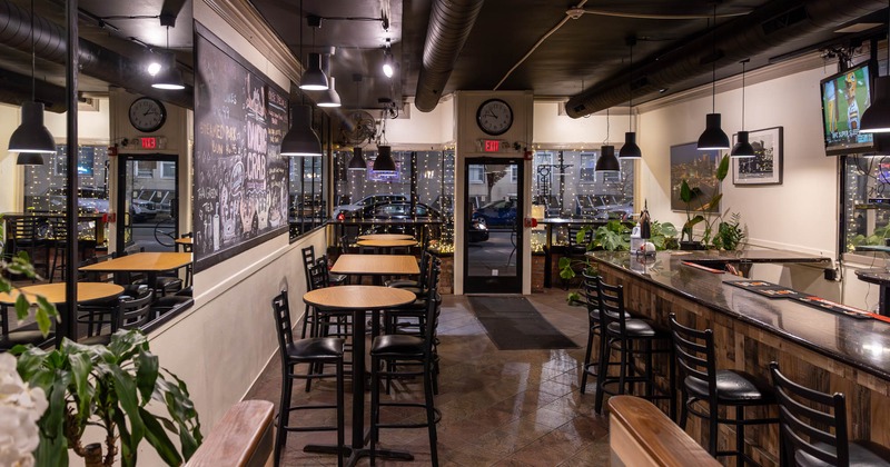 Interior, high seating tables on the left, bar on the right, restaurant entrance, shop window