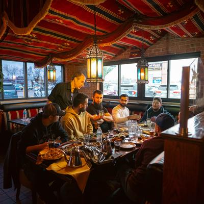 Interior, a server interacts with a group of guests at a dining table.