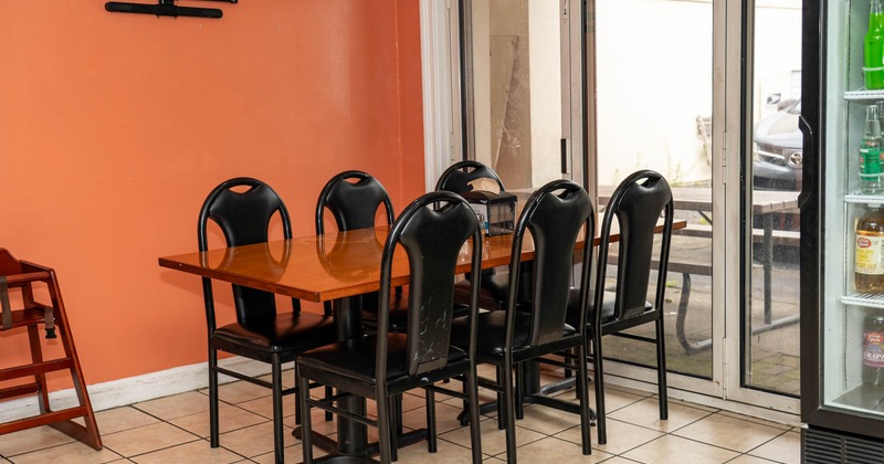 Indoor dining area with a wooden table, black chairs, and sliding glass doors leading outside