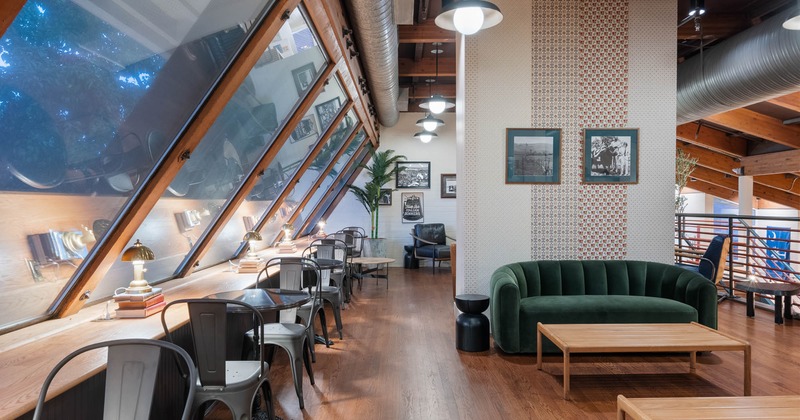 Interior, upstairs seating area, tables for two, large sofa with coffee table, framed photos