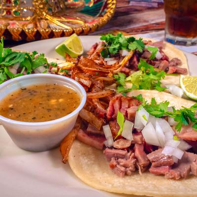 Street Tacos topped with diced onion and cilantro, served with a dip and lime wedges.