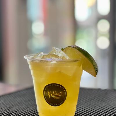 Iced drink in a plastic glass, garnished with a lime wedge.