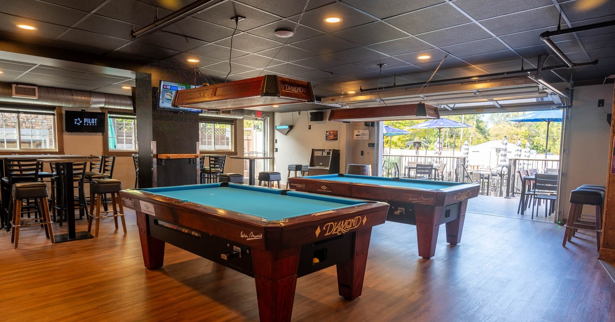 Interior, billiards tables, high seating area, large door leading to the patio