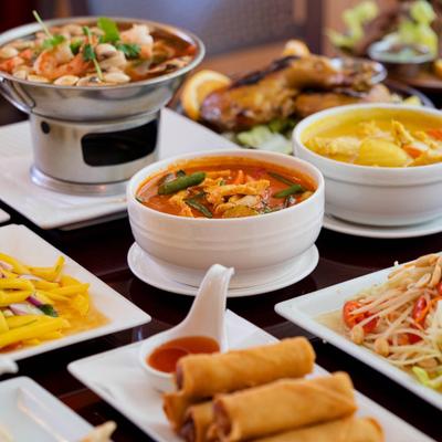 Assortment of Thai dishes, featuring Tom Yum soup, spring rolls, papaya salad, and curry.