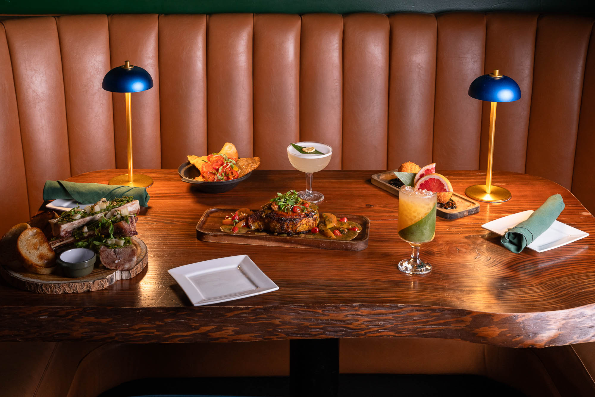 Assorted dishes and cocktails on a dimly-lit wooden table