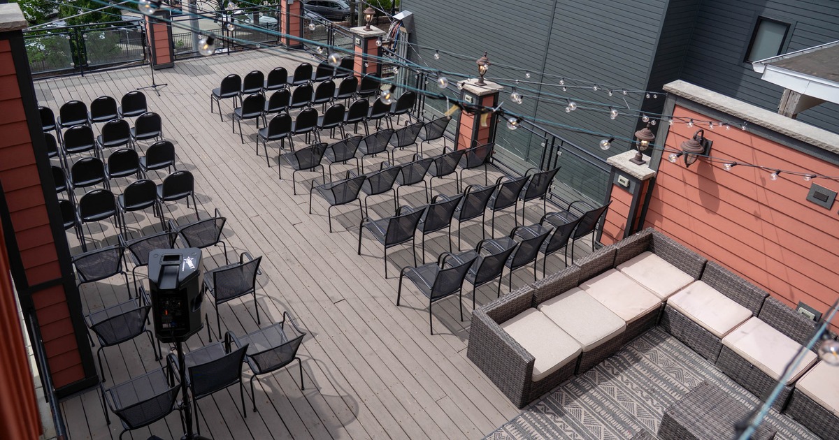 Rooftop patio with a with rows of black chairs and string lights