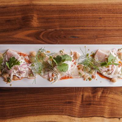 Seafood appetizer topped with herbs and presented on a long white plate.