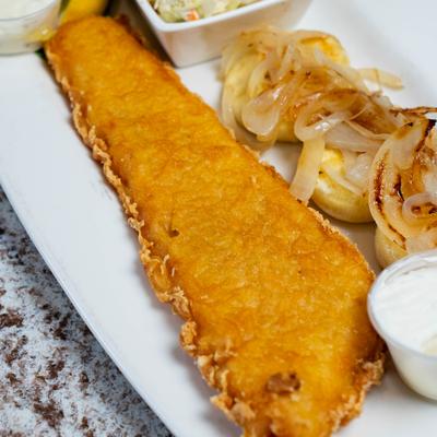 Fried fish filet and pierogi topped with onion, sides of coleslaw and dips.