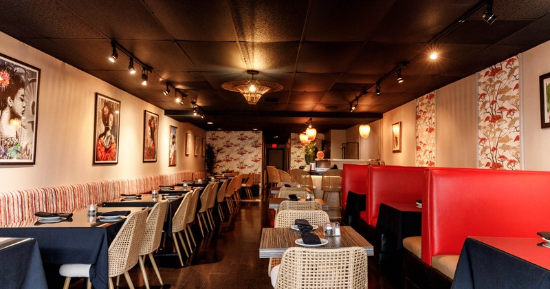 Interior seating area with framed portraits, red booths and woven chairs