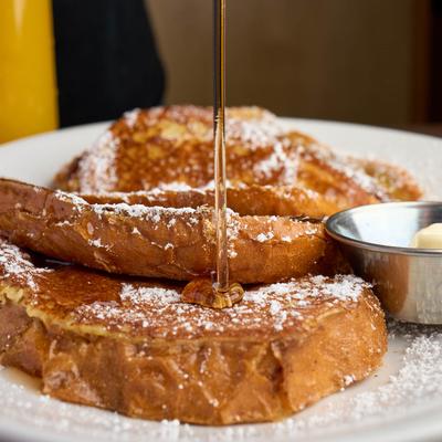 French toast with syrup, powdered sugar and a side of butter.