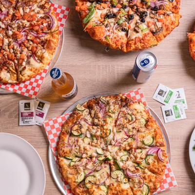 Overhead view of assorted pizzas and drinks on a table.