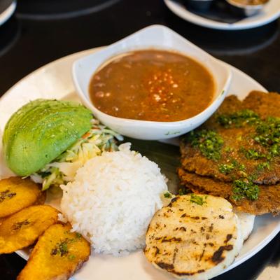 Vegan plate with arepa, avocado, plantain, salad, lentil patty, rice and beans.