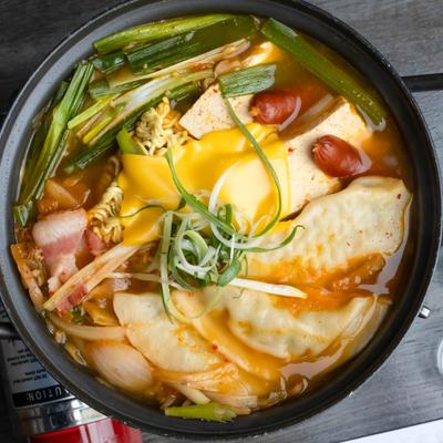 Spamy sausages, tofu, dumplings, kimchi, vegetables, ramen noodle and cheese.