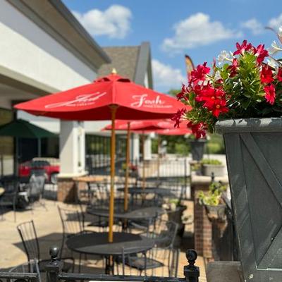 Outdoor patio with red umbrellas and table seating.