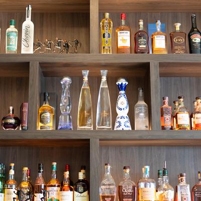 A wooden shelf display of assorted liquor bottles.