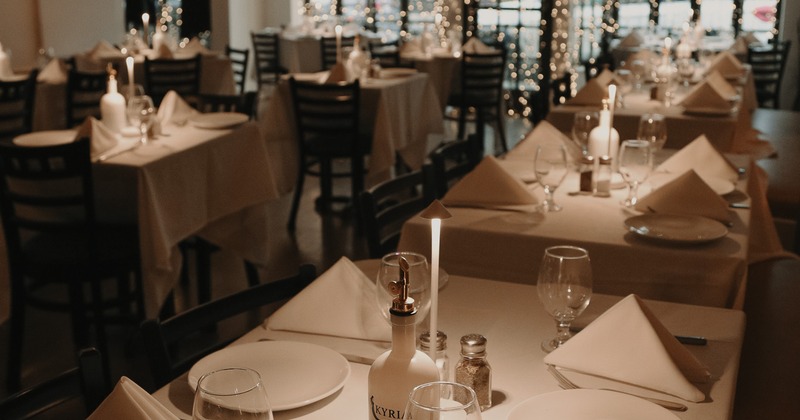 Dimly lit dining room with elegantly set tables and warm lighting