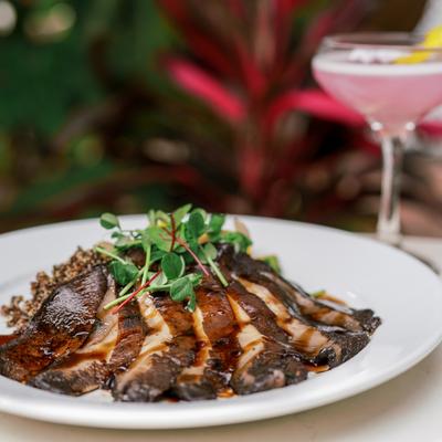 Sliced portobello mushroom steak with savory sauce, quinoa, and microgreens