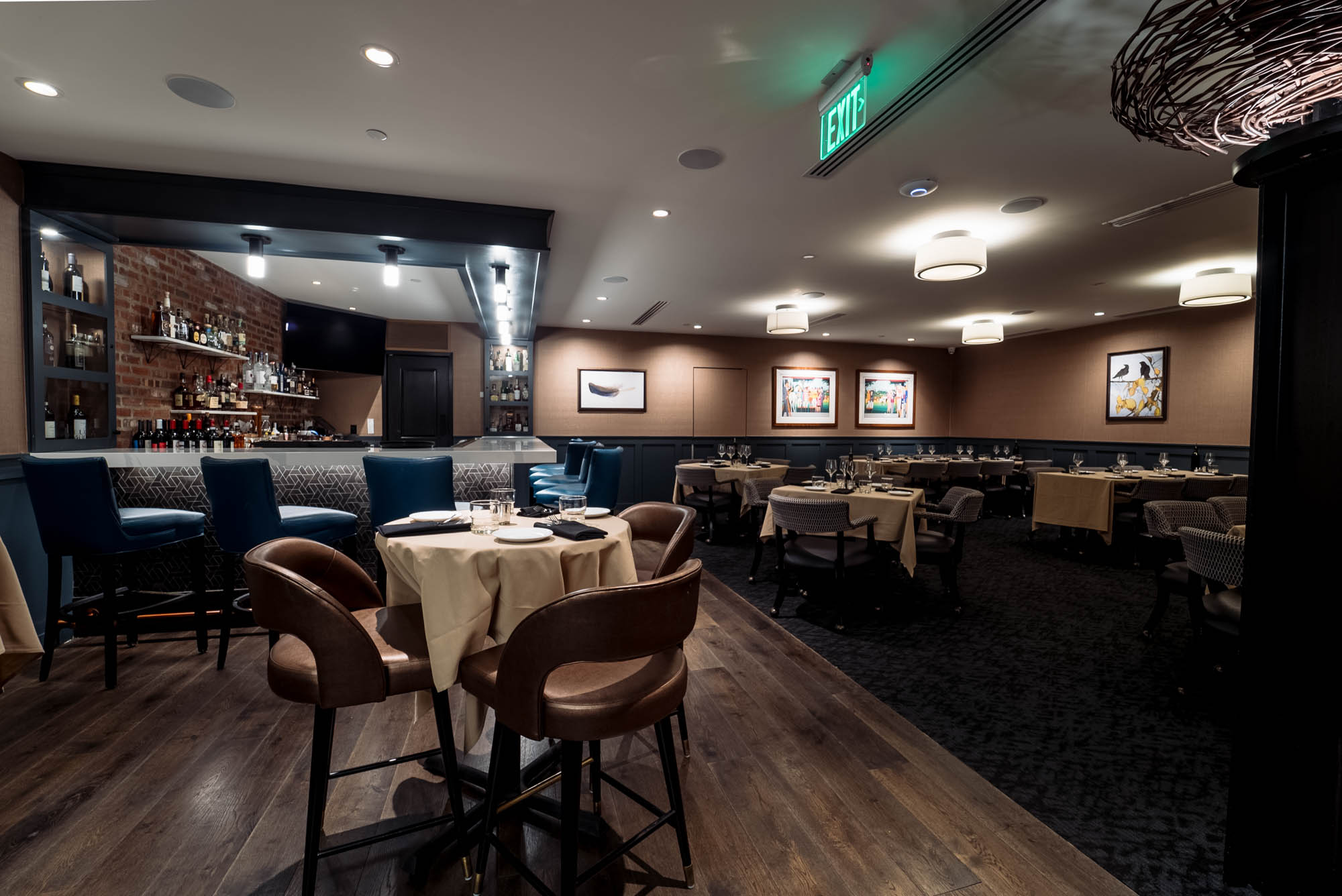 Dining area with a bar, set tables, chairs, and wall art