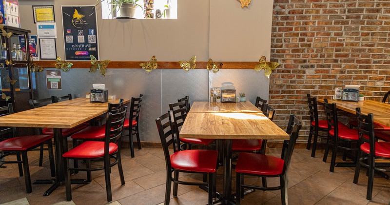 Restaurant dining room with wooden tables, black chairs with red seats