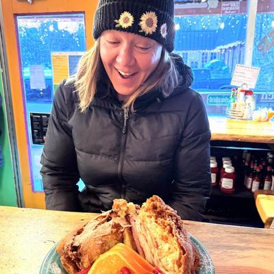 A smiling person looking at a served meal.