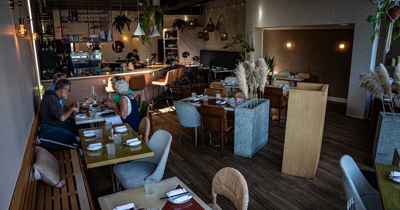 Restaurant interior, bar area and dining area with set dining tables, guests enjoying their food