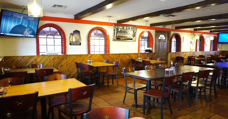 Rustic interior - wooden tables and chairs, brick arch windows and mounted televisions