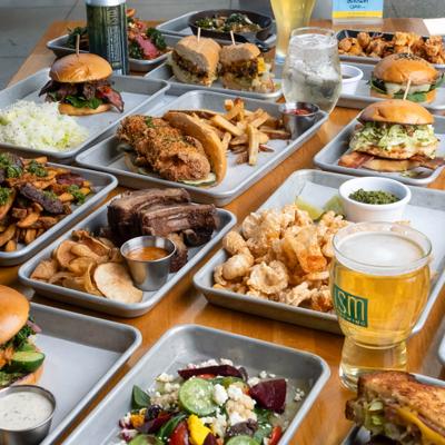 Large table spread of various dishes and glasses of craft beer.