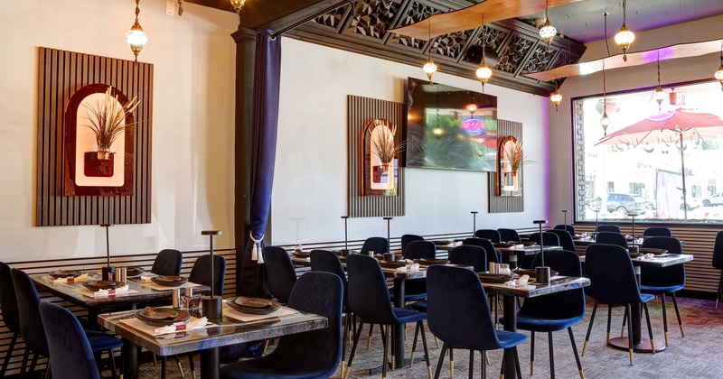Cozy restaurant interior dining area with blue velvet chairs and set tables