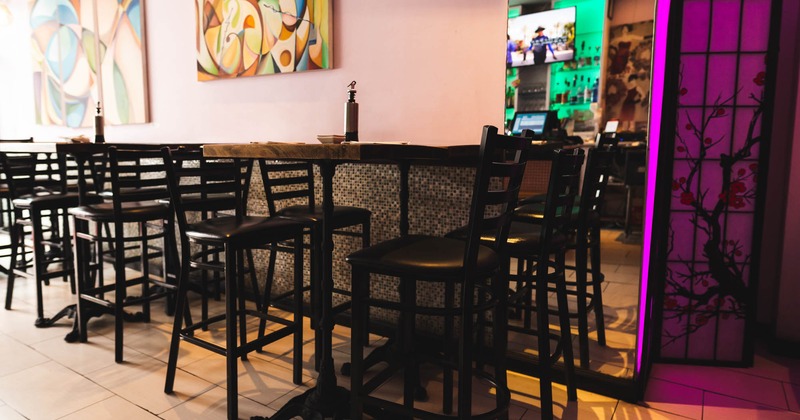Tall tables and bar stools by a wall decorated with artwork