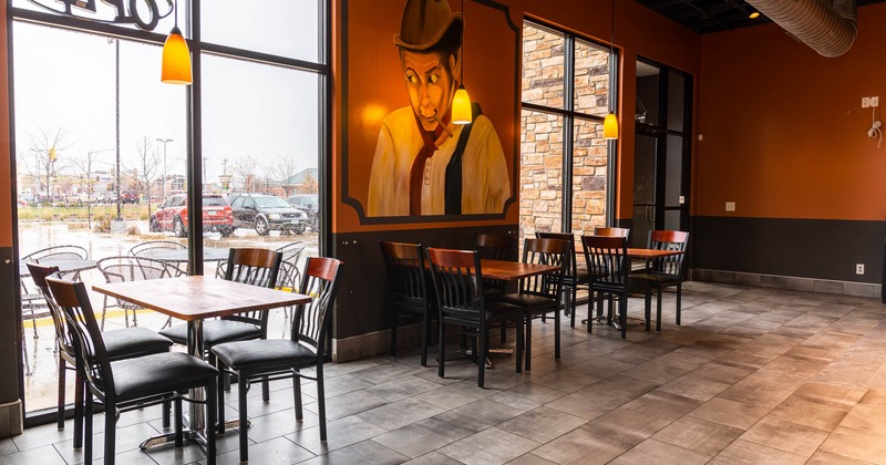 Interior, tables, chairs, wall mural, large windows, cars parked outside