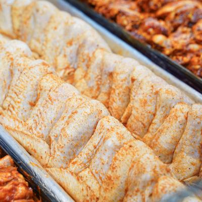 Raw, seasoned chicken parts arranged in a display tray.