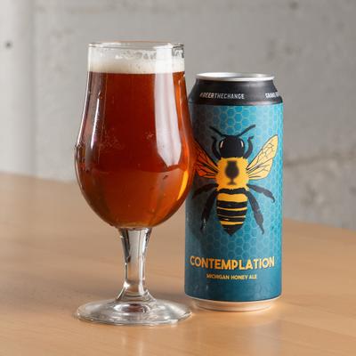 Can of beer featuring a prominent bee illustration, served beside a glass.