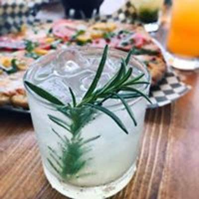 Rosemary gimlet cocktail on the rocks garnished with a rosemary sprig.
