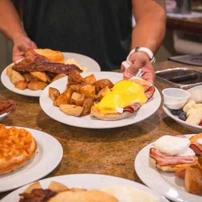 A server placing plates of breakfast dishes on the table.