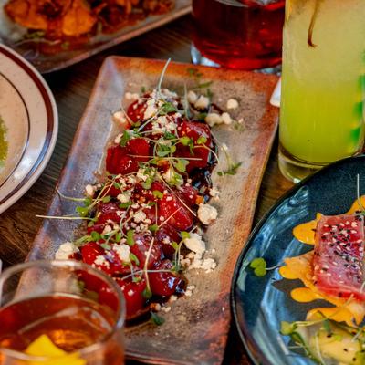 Multiple food dishes and cocktails on a wooden table.
