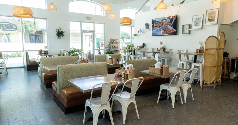 Modern restaurant with booths, white chairs, arched windows and decorative lighting