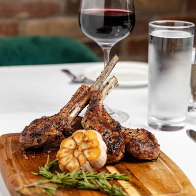 Lamb Chops served on a wooden board with roasted garlic and rosemary.