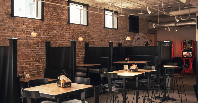 Interior with a mix of booth and table seating, brick wall and overhead lights