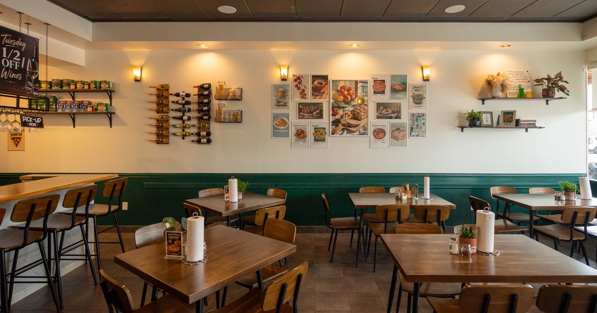 Interior - wooden tables and chairs; wine bottles and pictures on the wall.