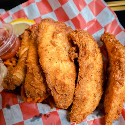 Fried haddock pieces served with a lemon wedge and dipping sauces.