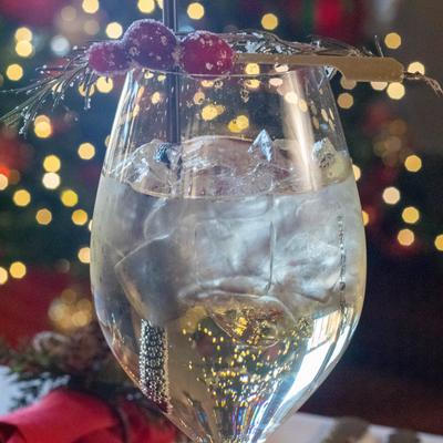 Transparent glass of iced cocktail with blurred Christmas lights in the background.