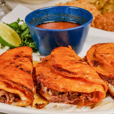Birria tacos served with consomme.