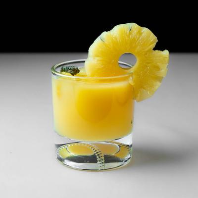A yellow drink garnished with a pineapple slice.