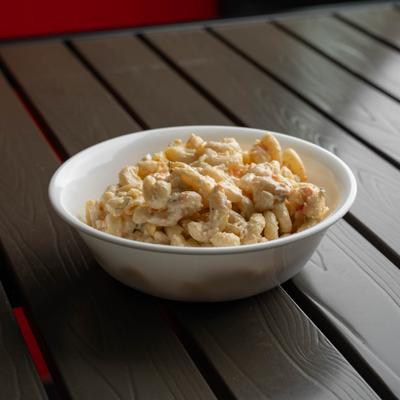 Bowl of macaroni salad on a wooden table.