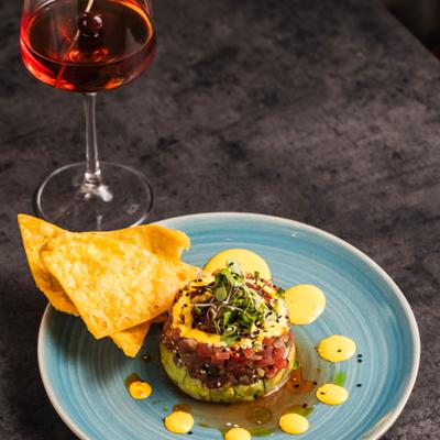 Tuna Tartare served with tortilla chips, alongside a cocktail.