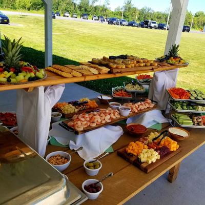 Grazing table setup with fruits, vegetables, cured meats, cheeses and shrimp cocktail.