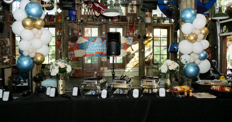 A table with balloons, flowers, and chafing dishes