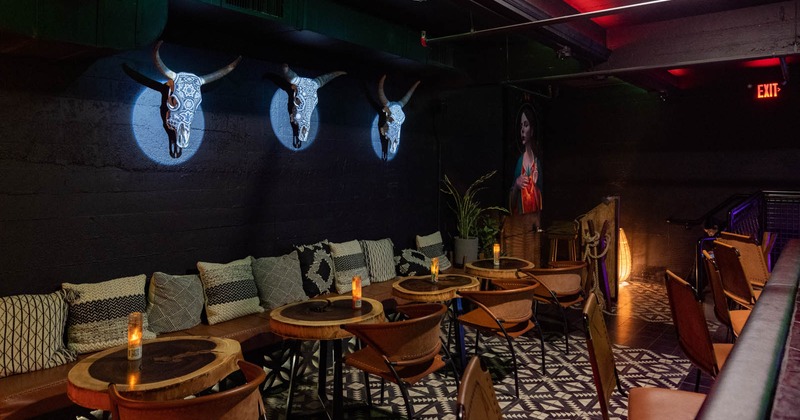 Seating area, wall seating with pillows, round tables and chairs, decorated cow skulls on a wall