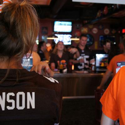 A crowd of people watching the game, waitress in the foreground