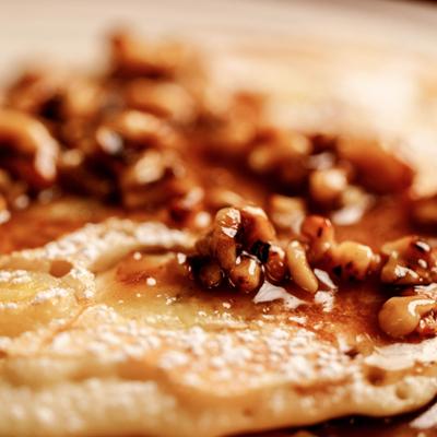 Pancake topped with walnuts and syrup, close up.